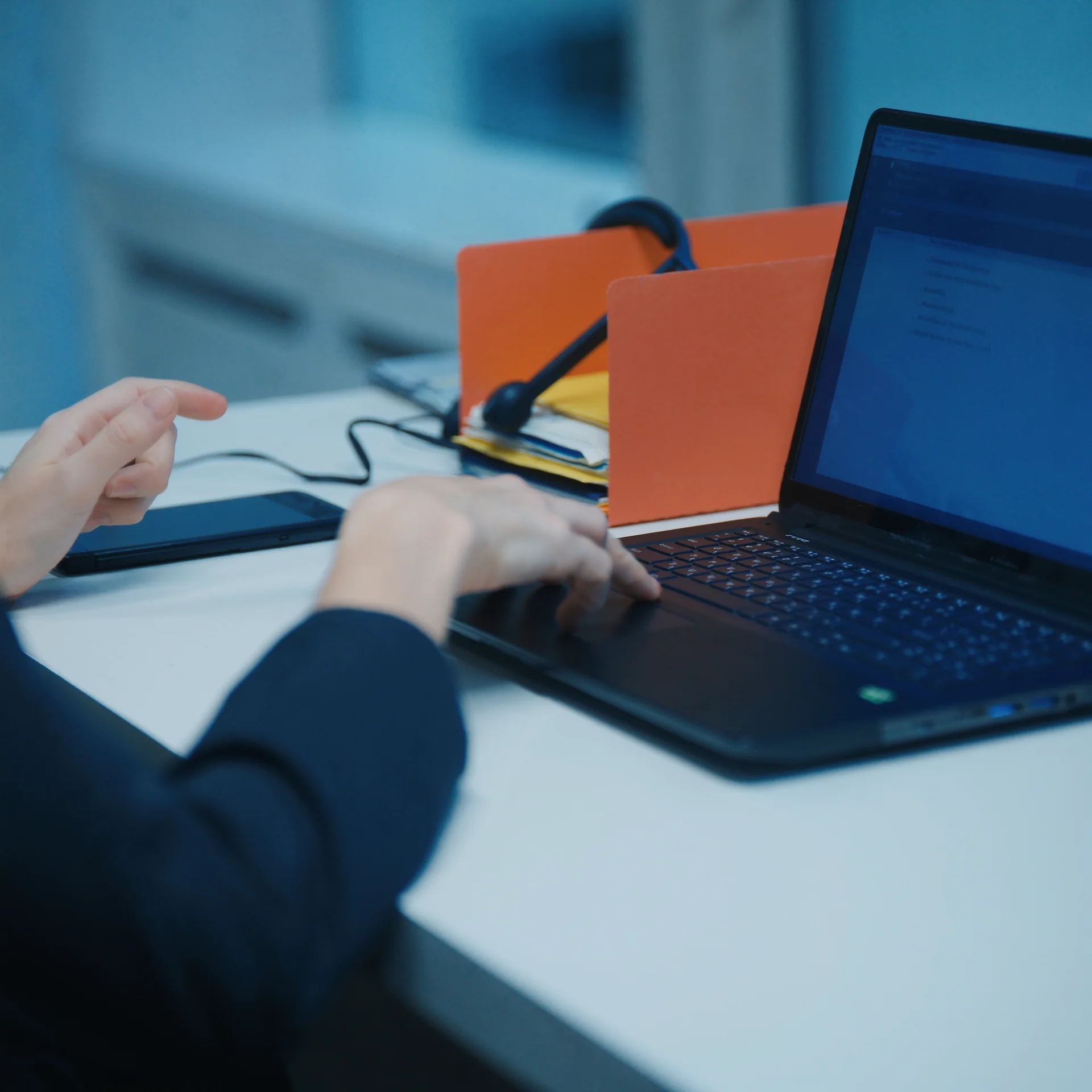 Profissional trabalhando em mesa organizada com laptop e pastas